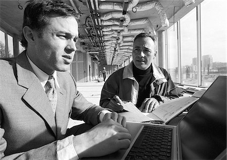 exterior bay window photos - Man looking at agenda, second man using laptop computer, b&w Stock Photo - Premium Royalty-Free, Code: 695-05776101