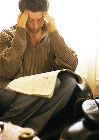 Man rubbing head with newspaper on knees Foto de stock - Sin royalties Premium, Código: 695-05776149