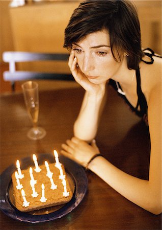 Woman alone at table with cake and candles Stock Photo - Premium Royalty-Free, Code: 695-05776238