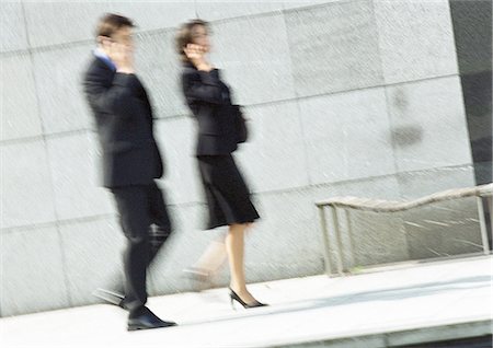 professional phone outside walking - Businessman and woman using cell phones in street, full length, blurred motion Stock Photo - Premium Royalty-Free, Code: 695-05776257