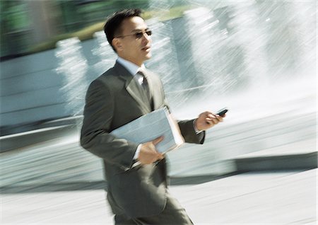 simsearch:695-05776257,k - Businessman walking with cell phone in hand, three quarter length, tilt Stock Photo - Premium Royalty-Free, Code: 695-05776264