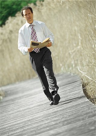 Businessman walking with newspaper in hands, outdoors, portrait Stock Photo - Premium Royalty-Free, Code: 695-05776268