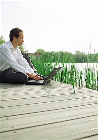 Man sitting outdoors with laptop computer Stock Photo - Premium Royalty-Free, Code: 695-05776298
