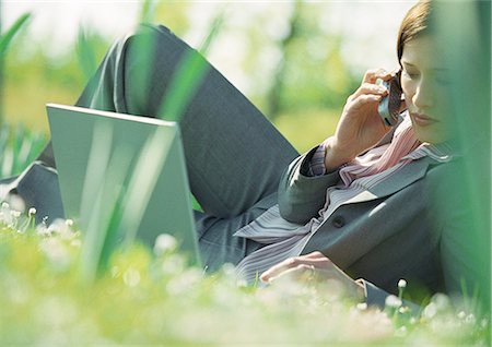 Businesswoman lying on grass with laptop and cell phone Stock Photo - Premium Royalty-Free, Code: 695-05776308