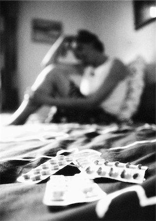 simsearch:649-09207396,k - Woman sitting on bed, pills in foreground, blurred, b&w Foto de stock - Sin royalties Premium, Código: 695-05776356