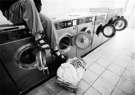 sandals lined up - Person sitting on washing machine in laundrymat, low section, b&w Stock Photo - Premium Royalty-Free, Code: 695-05776368