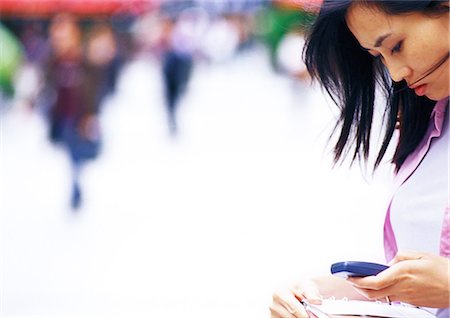 pedestrian side - Businesswoman looking at cell phone, side view, close-up, off center Stock Photo - Premium Royalty-Free, Code: 695-05776513