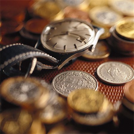 Wristwatch on top of assorted coins Stock Photo - Premium Royalty-Free, Code: 695-05776609