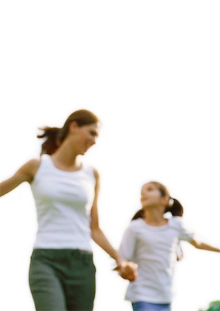 Woman and girl looking at each other and holding hands, blurred motion, low angle view Stock Photo - Premium Royalty-Free, Code: 695-05776896