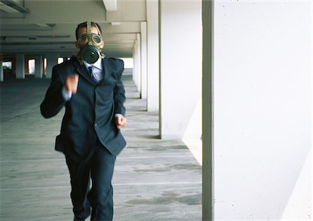 scared running - Businessman running with gas mask covering face Stock Photo - Premium Royalty-Free, Code: 695-05776909