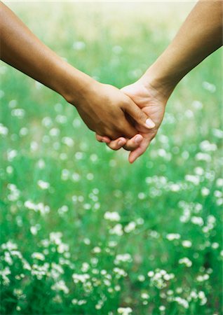 Clasped hands in front of grass with wildflowers Stock Photo - Premium Royalty-Free, Code: 695-05776921