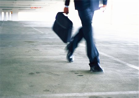 Businessman walking, lower section, blurred Stock Photo - Premium Royalty-Free, Code: 695-05776944