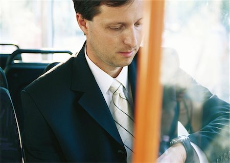 Businessman sitting on bus, checking watch Foto de stock - Sin royalties Premium, Código: 695-05776947