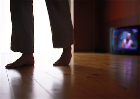 feet walking indoors - Man walking across hardwood floor past television, surface level Stock Photo - Premium Royalty-Free, Code: 695-05776972