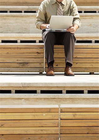 Homme assis à l'extérieur, en utilisant un ordinateur portable, rognée de cou vers le bas Photographie de stock - Premium Libres de Droits, Code: 695-05777004