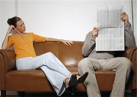 Man and woman sitting on sofa, man reading newspaper Stock Photo - Premium Royalty-Free, Code: 695-05777023
