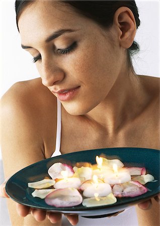 simsearch:695-05777392,k - Woman holding plate of aromatic candles and rose petals, looking down, close-up Foto de stock - Sin royalties Premium, Código: 695-05777393