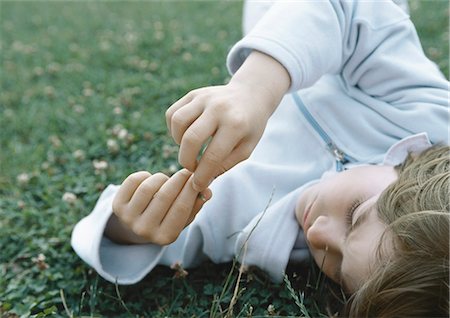 Boy lying on grass holding fingers together in front of face Stock Photo - Premium Royalty-Free, Code: 695-05777429
