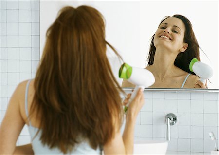 Woman drying hair in front of mirror Stock Photo - Premium Royalty-Free, Code: 695-05777453