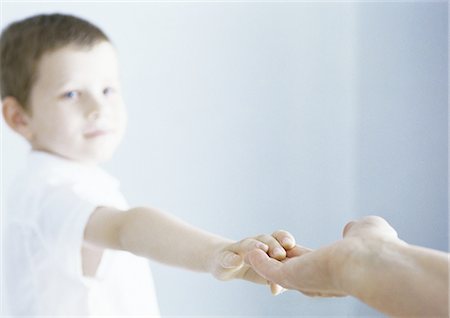 Boy reaching out to touch adult's hand Stock Photo - Premium Royalty-Free, Code: 695-05777485