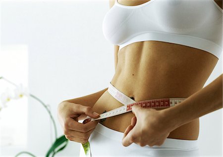 flat belly - Woman measuring waist, mid section Stock Photo - Premium Royalty-Free, Code: 695-05777481