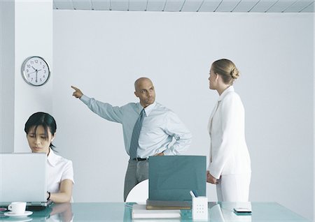 Boss pointing at clock and looking sternly at employee Stock Photo - Premium Royalty-Free, Code: 695-05777536