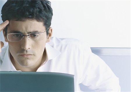 Businessman looking at computer, furrowing brow Stock Photo - Premium Royalty-Free, Code: 695-05777567