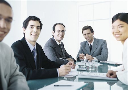 simsearch:695-05763908,k - Businesspeople sitting around table, smiling at camera Fotografie stock - Premium Royalty-Free, Codice: 695-05777621