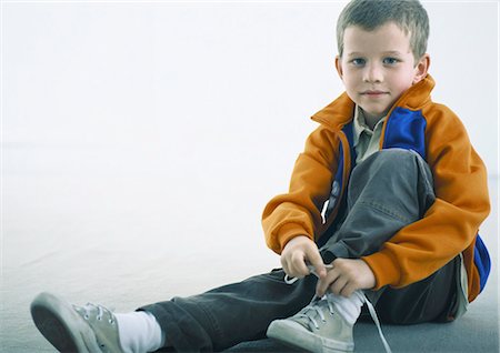 Boy sitting on floor, tying shoe Stock Photo - Premium Royalty-Free, Code: 695-05777635