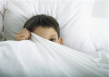 Boy in bed, peeking out behind sheet with one eye Foto de stock - Sin royalties Premium, Código: 695-05777670