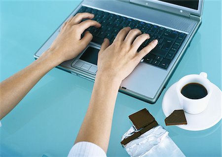 Woman typing on laptop, chocolate and coffee on desk Stock Photo - Premium Royalty-Free, Code: 695-05777738