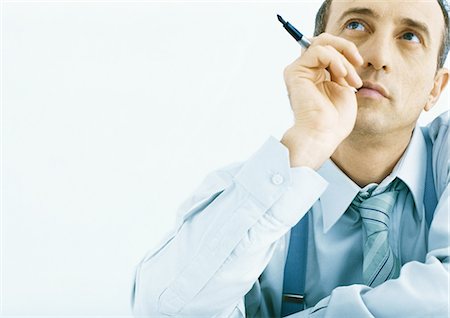 Man holding pen near face, looking up Foto de stock - Sin royalties Premium, Código: 695-05777785