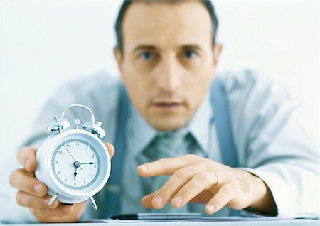 Man holding out alarm clock, focus on hands and clock in foreground Foto de stock - Sin royalties Premium, Código: 695-05777786