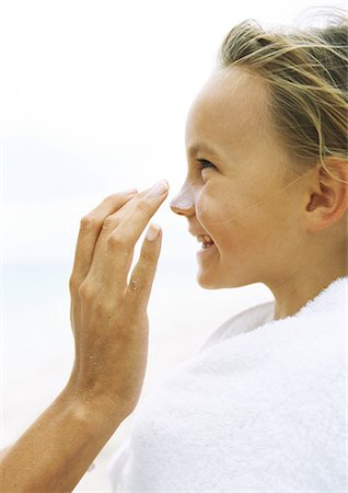 simsearch:400-03930224,k - Little girl wrapped in towel having sunscreen rubbed into nose by mother Fotografie stock - Premium Royalty-Free, Codice: 695-05777915