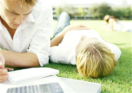 simsearch:649-06812666,k - Students lying on grass, young man studying, young woman lying on back Fotografie stock - Premium Royalty-Free, Codice: 695-05777979