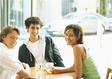 Group of young people sitting at table in café, smiling at camera Stock Photo - Premium Royalty-Free, Code: 695-05778019