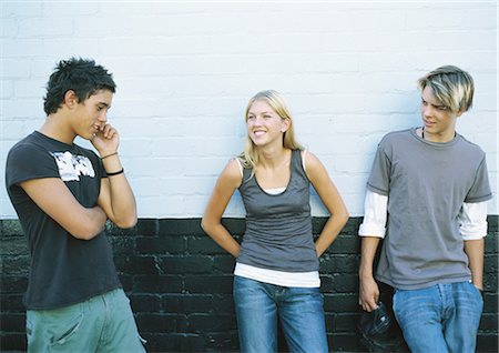 simsearch:695-05764970,k - Young people leaning against wall, one using cell phone, front view Stock Photo - Premium Royalty-Free, Code: 695-05778022