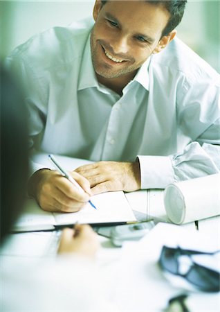 simsearch:632-01155457,k - Man smiling while writing in agenda, looking at second person Stock Photo - Premium Royalty-Free, Code: 695-05778232