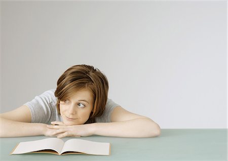 Young woman sitting with head on table next to open notebook Stock Photo - Premium Royalty-Free, Code: 695-05778459