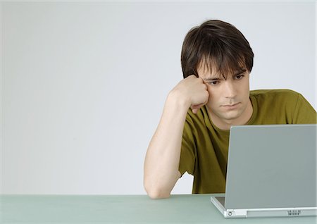 simsearch:632-08887035,k - Young man using laptop, leaning on elbow Fotografie stock - Premium Royalty-Free, Codice: 695-05778465