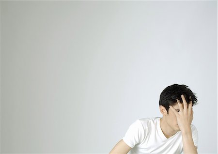 Young man covering face with hand Stock Photo - Premium Royalty-Free, Code: 695-05778460