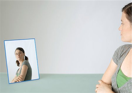Young woman looking at self in mirror, portrait Stock Photo - Premium Royalty-Free, Code: 695-05778483