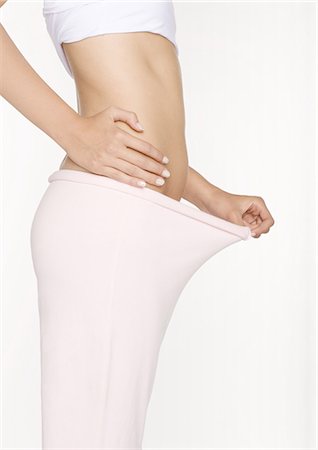 female body waist - Young woman holding out pants, mid section Stock Photo - Premium Royalty-Free, Code: 695-05778664