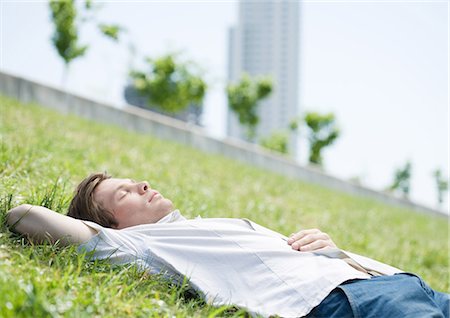 Young man lying on grass in urban park Stock Photo - Premium Royalty-Free, Code: 695-05778777