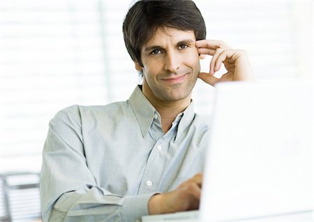 Man sitting at laptop, smiling Stock Photo - Premium Royalty-Free, Code: 695-05778796