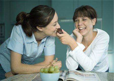 people laughing magazine - Mother eating fruit from daughter's hand Stock Photo - Premium Royalty-Free, Code: 695-05779031