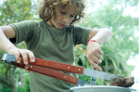 Boy picking up piece of meat from plate Stock Photo - Premium Royalty-Free, Code: 695-05779128