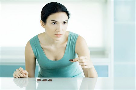 Woman eating chunks of chocolate, looking away Stock Photo - Premium Royalty-Free, Code: 695-05779142