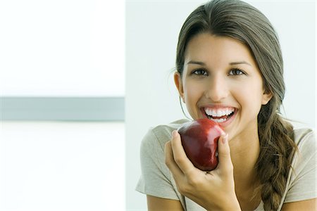 Young female holding apple, smiling at camera, portrait Stock Photo - Premium Royalty-Free, Code: 695-05779213