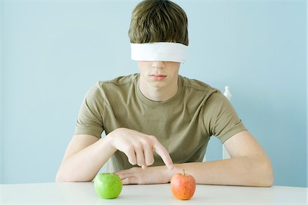 enigma - Teen boy wearing blindfold, pointing to red apple Stock Photo - Premium Royalty-Free, Code: 695-05779224